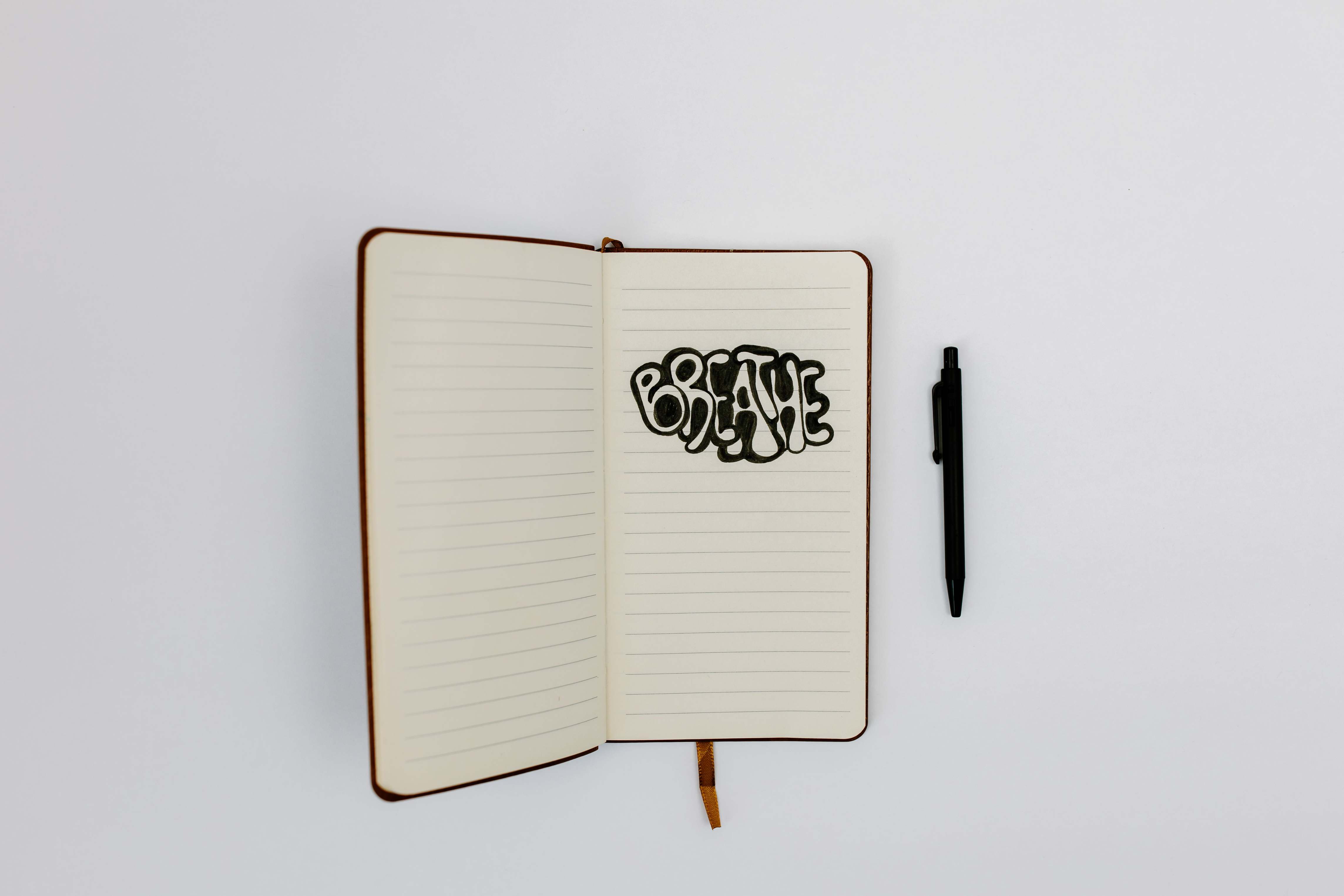 Notebook and pen on a desk seen from above on a white surface