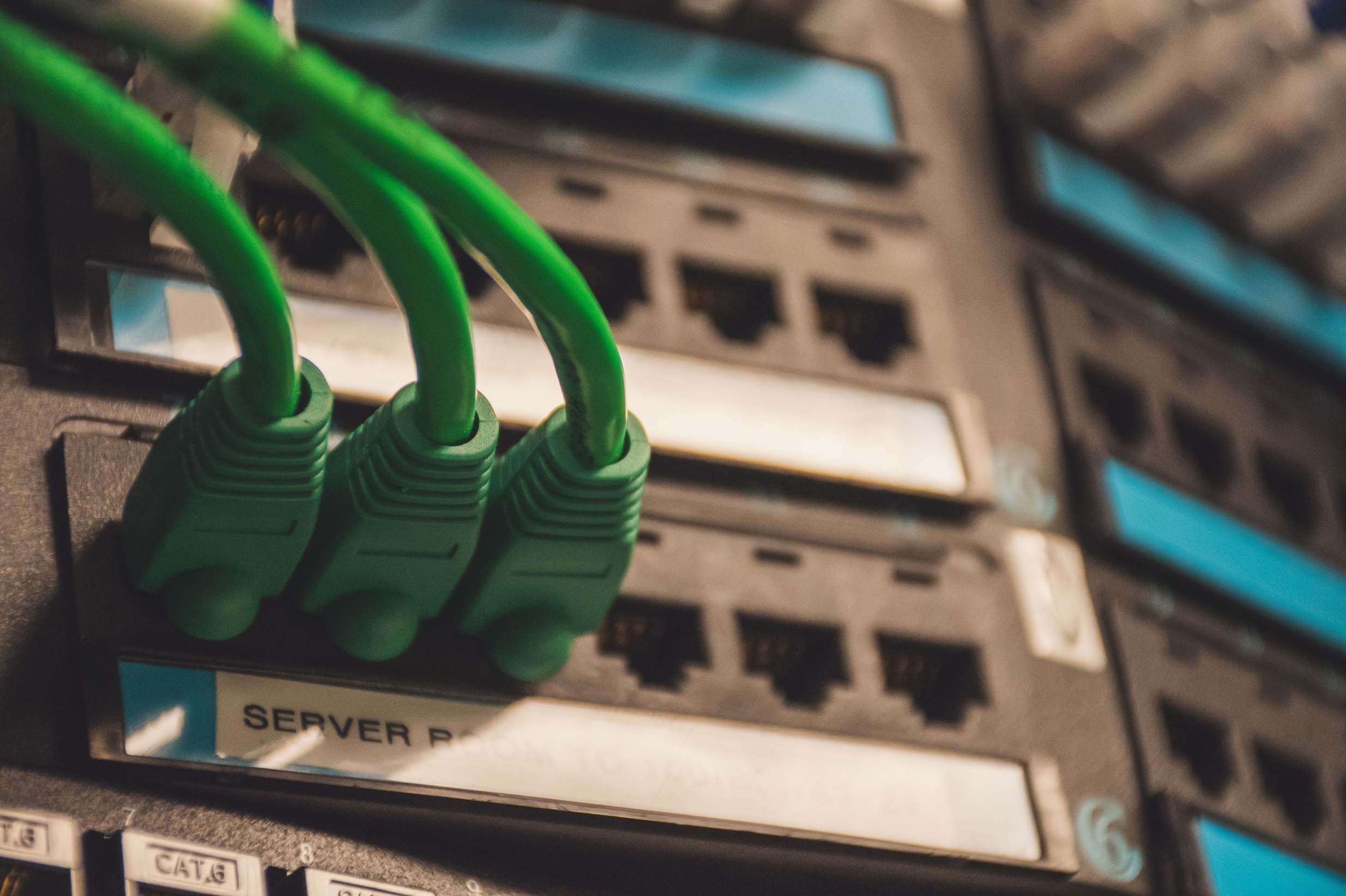 Server hardware in a data center aisle with green network cables in server ports
