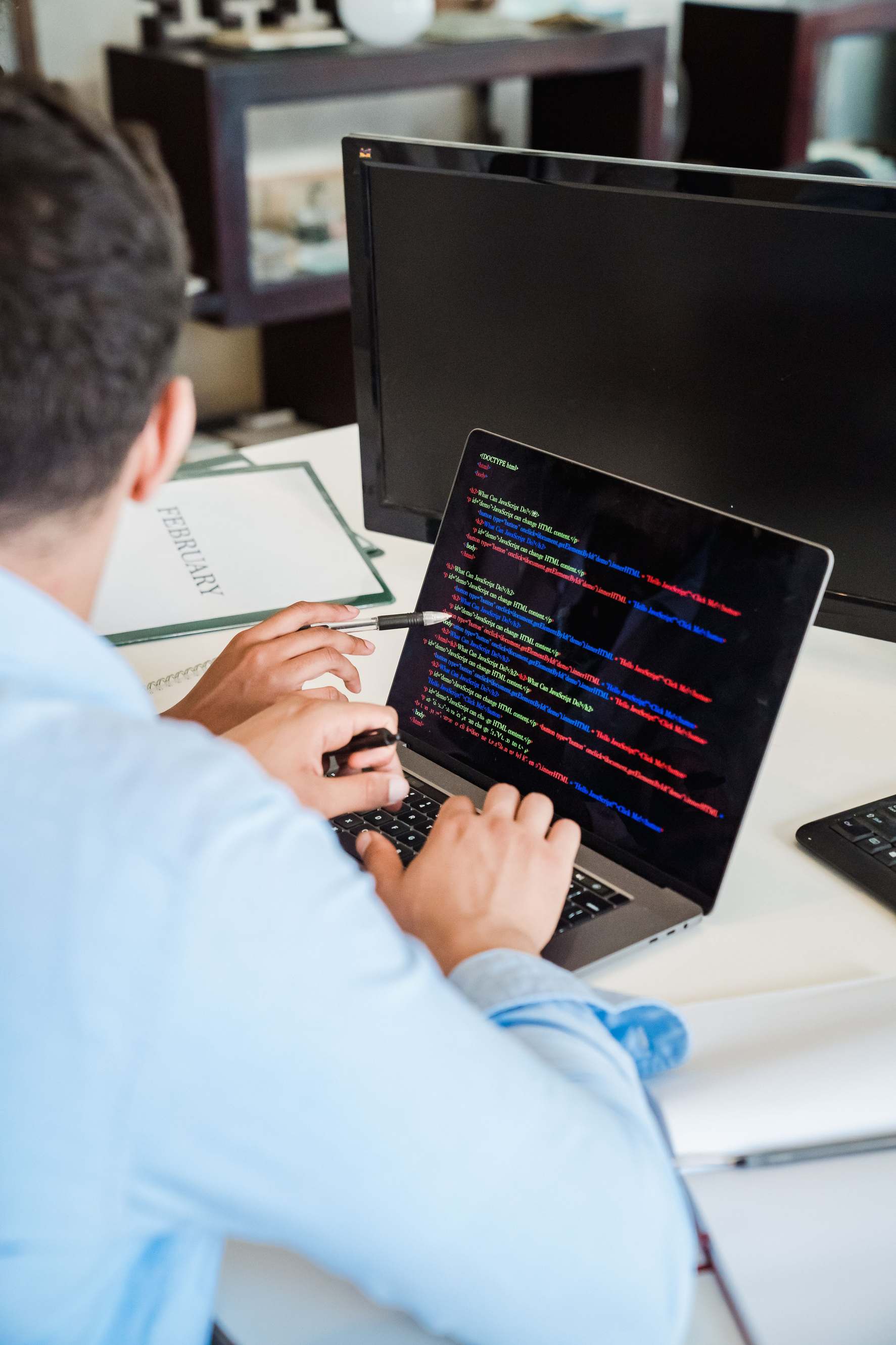Developer workspace with laptop showing software on screen beside coding setup